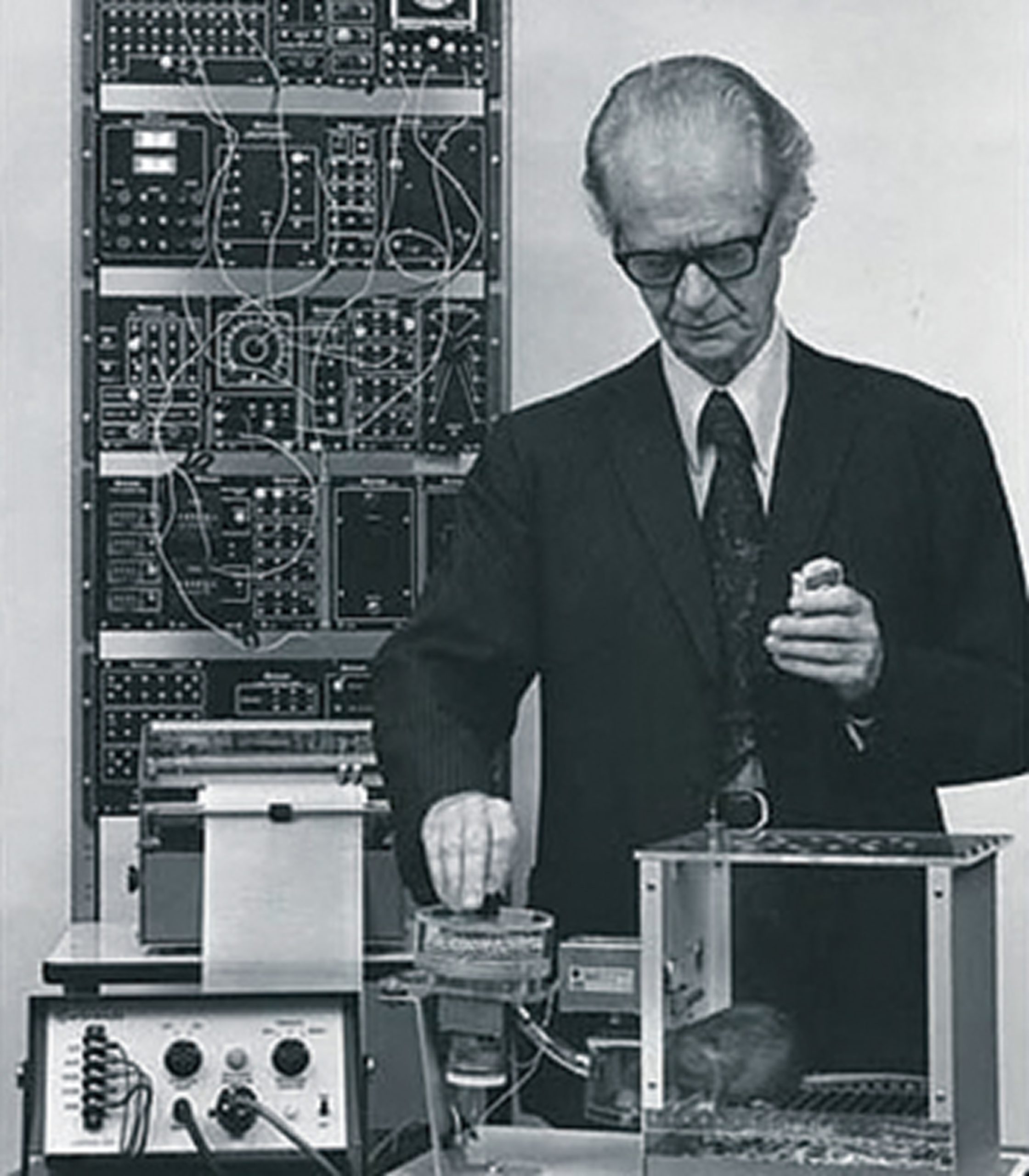 Burrhus Skinner, photographed in his Harvard laboratory with a rat, operant chamber and control equipment at the rear.