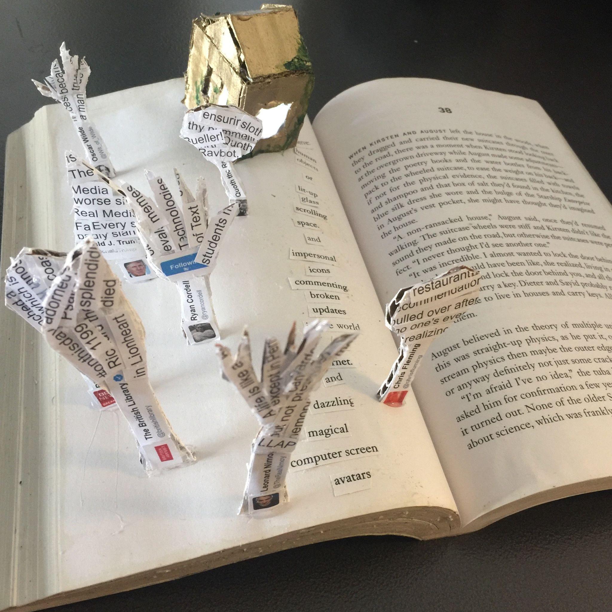 Paper sculpture of house and trees in an open book