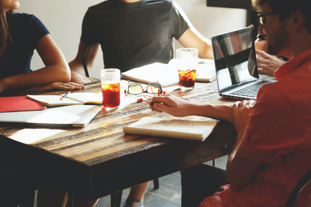 Group of people having a meeting with soft drinks, notebooks and a laptop