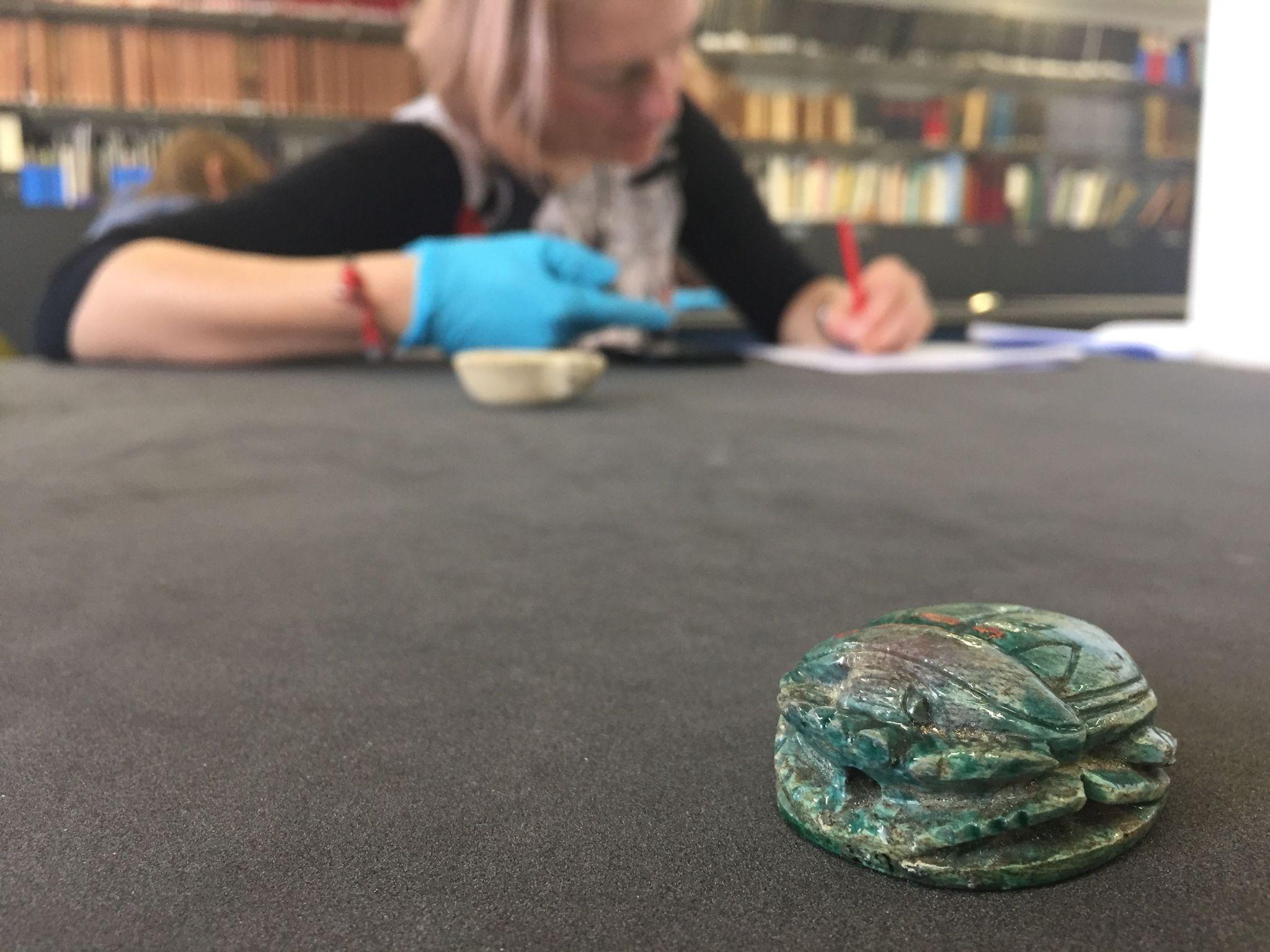 A Victorian forged Egyptian scarab beetle in the foreground, during an object-based learning ‘ways of looking’ learning activity in the Hunterian Museum teaching collections.