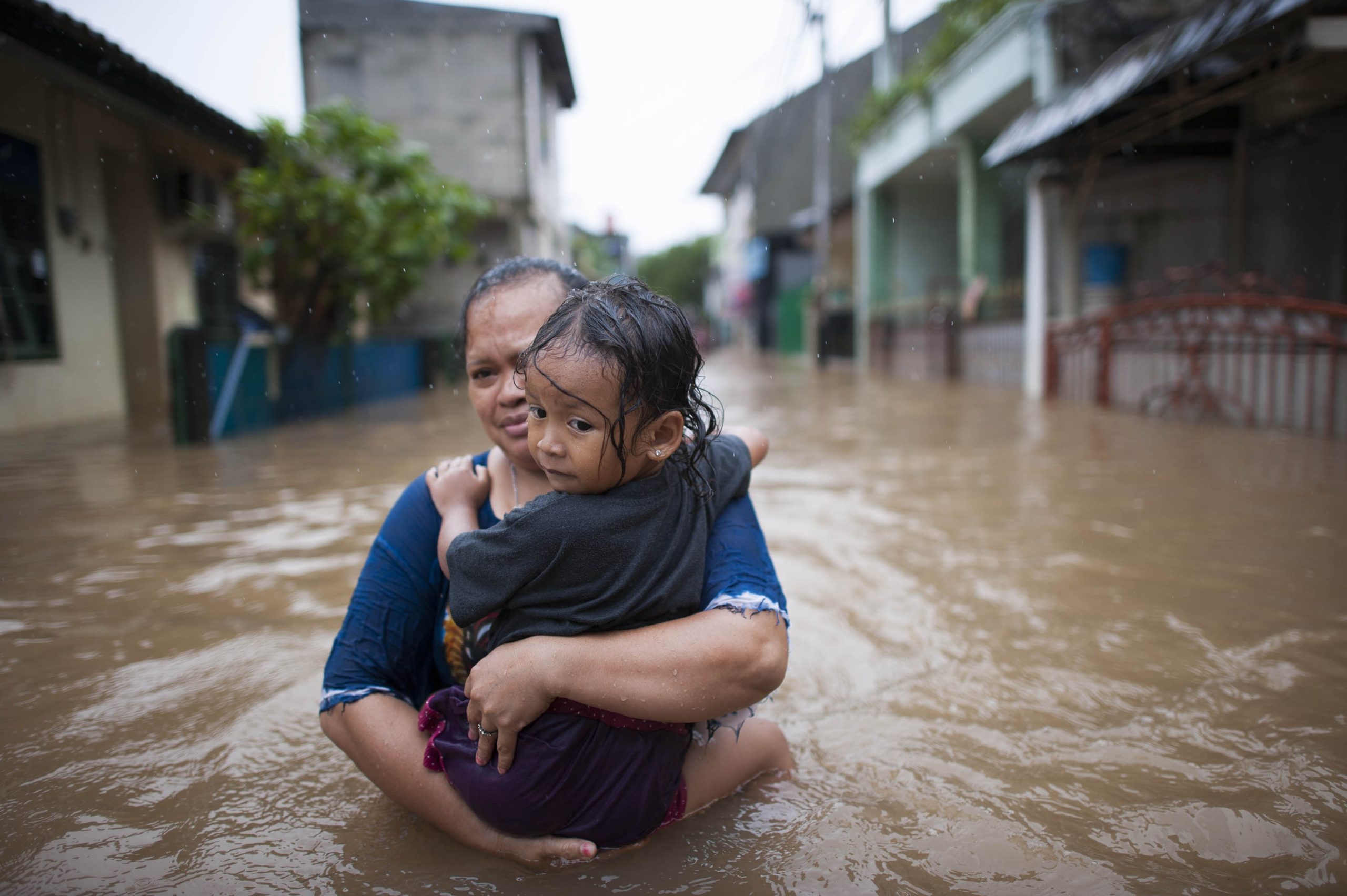 Woman carrying her child waist-deep in floodwater, Jakarta