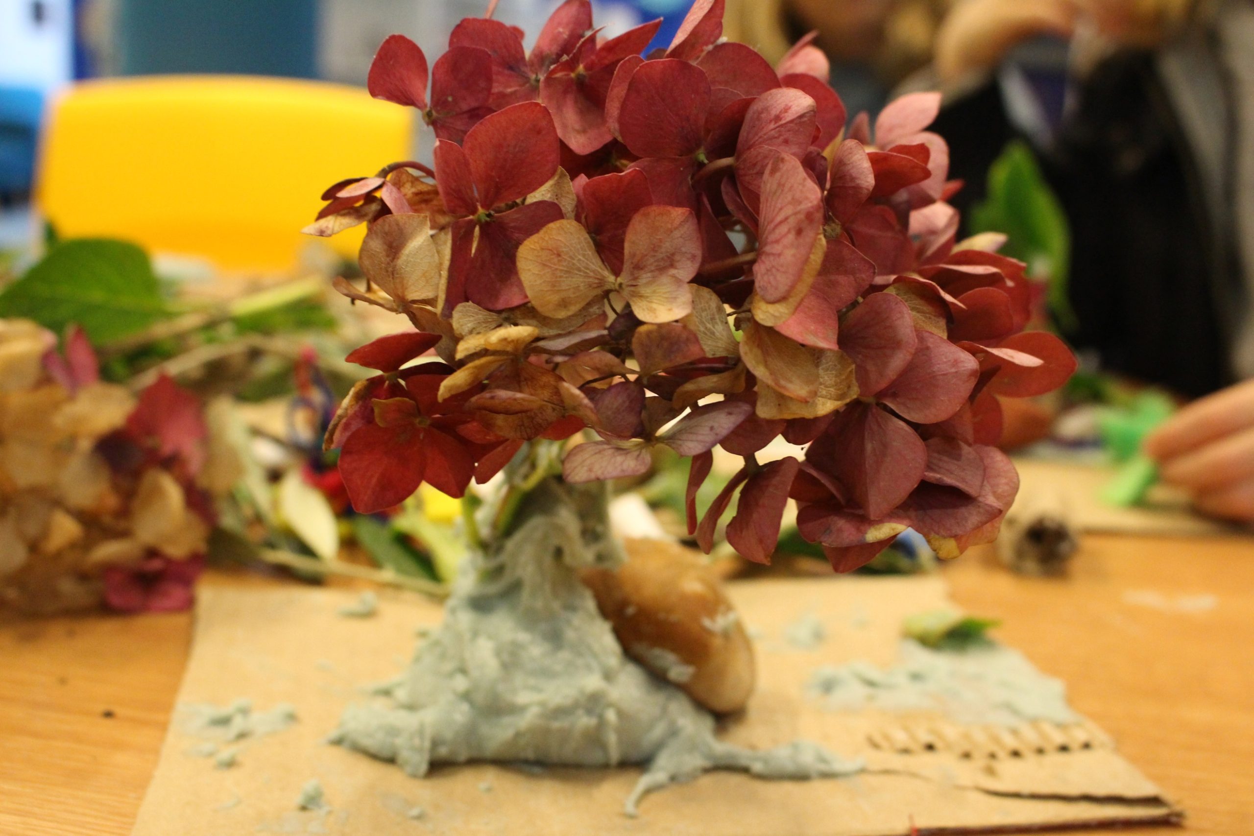 Photograph of a desk with a small sculpture of a tree crafted from a hydrangea flower and saltdough