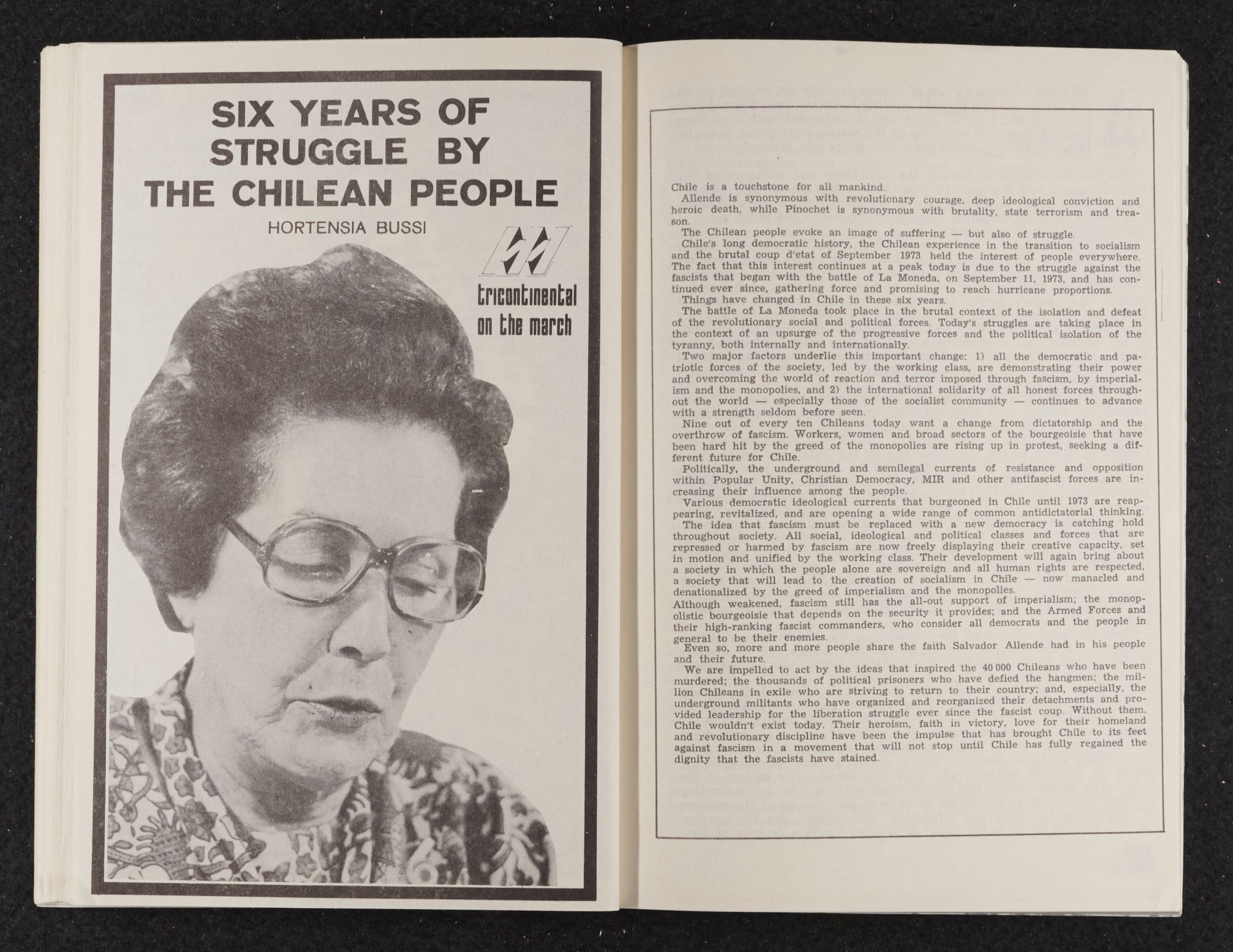 Image credit: Copyright OSPAAAL (1980). Tricontinental Magazine, Issue 67/68, pages 71-72. Accessed via British Library for Development Studies Legacy Collection. Scan copyright University of Sussex (2024). Used with kind permission. All rights reserved. A booklet open on a double-page spread. The right-hand side is a full page of text. The left-hand side has the title 'Six Years of Struggle by the Chilean People', and a photo of a woman wearing glasses and a flowery dress and looking down with her lips pursed as though she is reading something aloud.