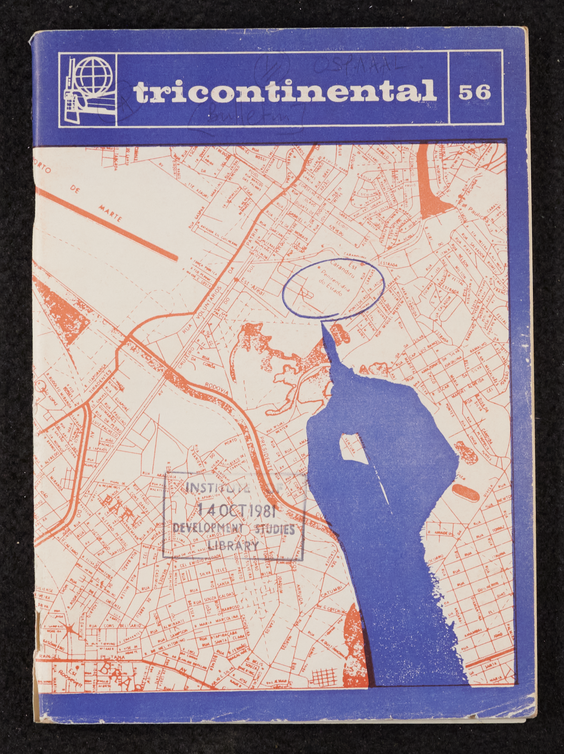 Image credit: Copyright OSPAAAL (1970). Tricontinental Review, No. 56: Front cover. Accessed via British Library for Development Studies Legacy Collection. Scan courtesy University of Sussex (2024). All rights reserved. The front cover of Issue 56 has a royal blue header banner with 'tricontinental' in lower case, the logo and the issue number. The main graphic is a street map in orange ink of part of Sao Paolo. Overlaying the map is the silhouette of a hand holding a pen, in the same blue. The hand has circled a small area of the map enclosing the Penitenciaria do Estado - the prison Carandiru.