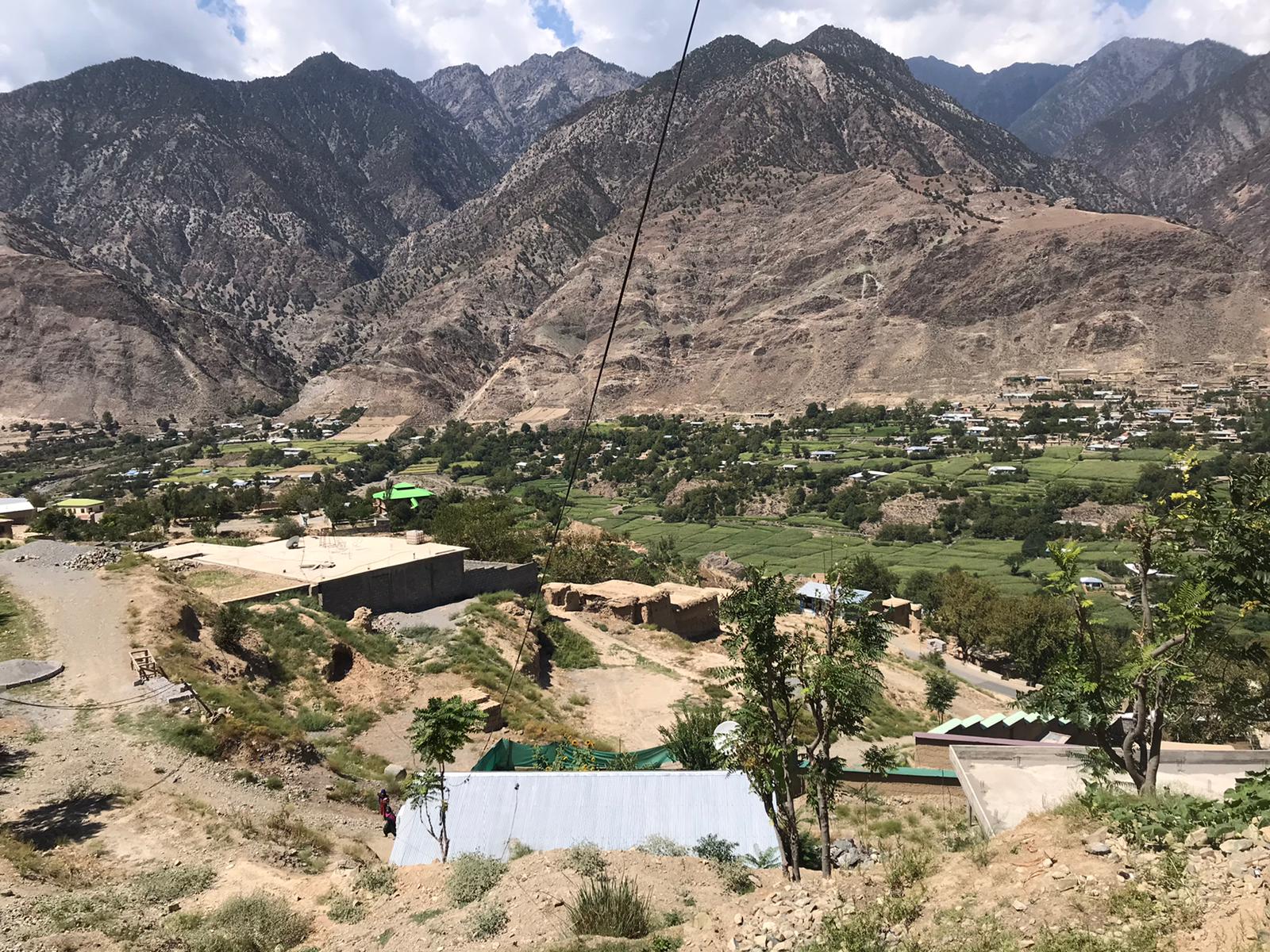 Photo of a refugee camp. The camp is in a valley surrounded by mountains.
