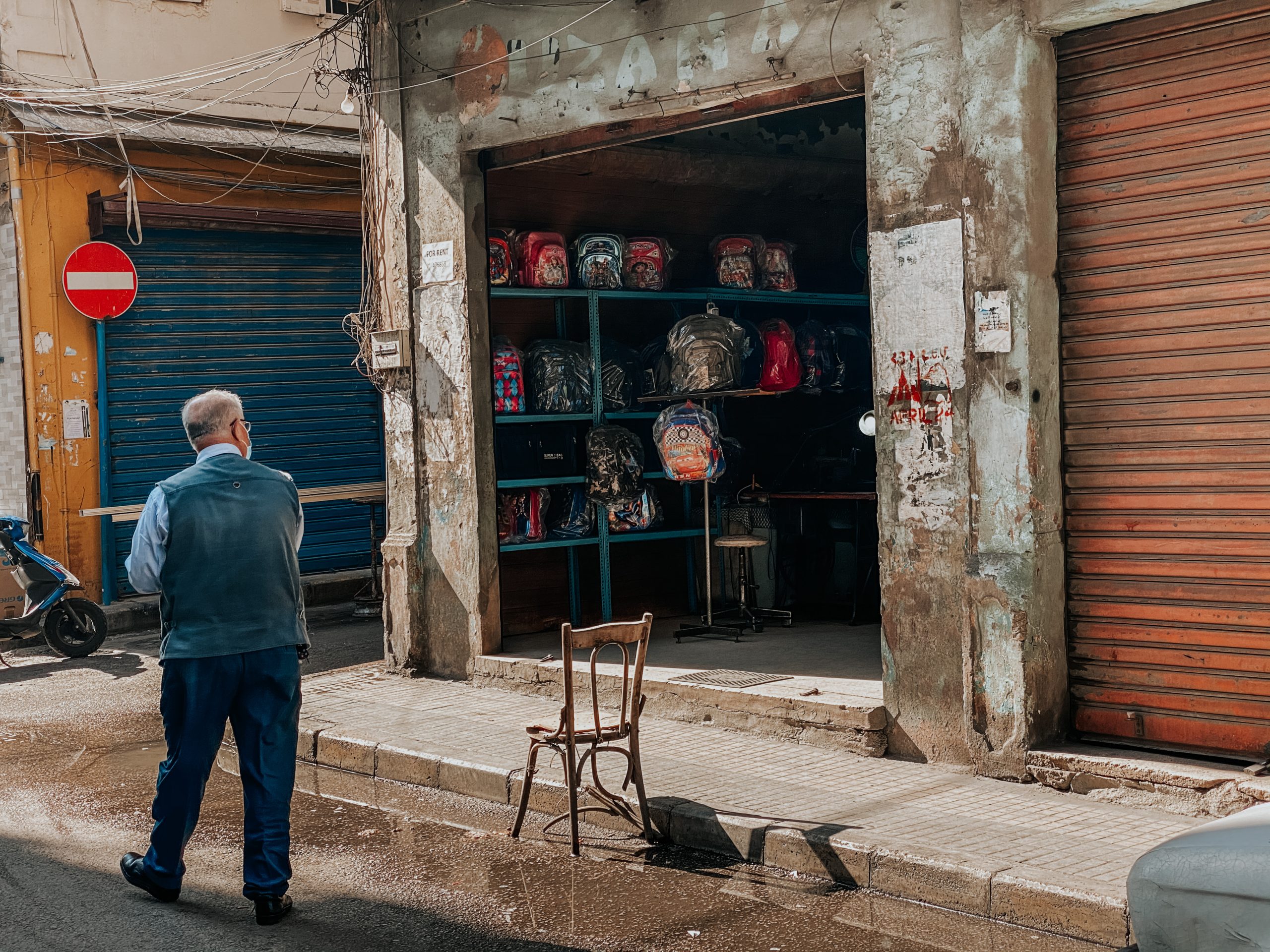Photo of a man walking past a shopfront.